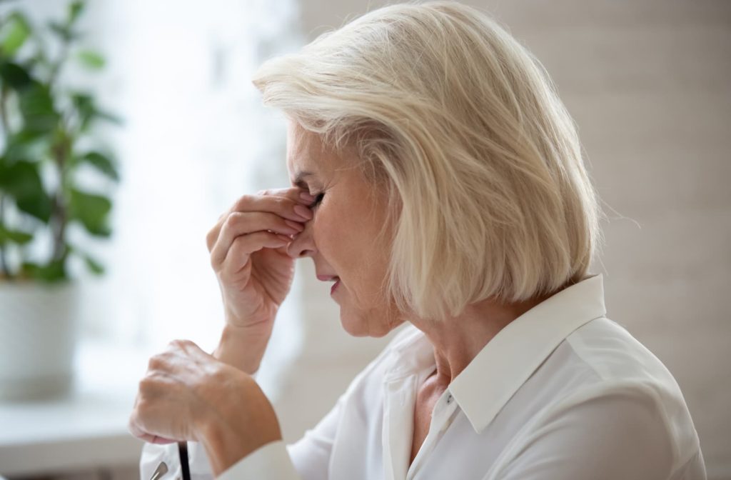 Older woman rubbing her eyes because of dry eye.