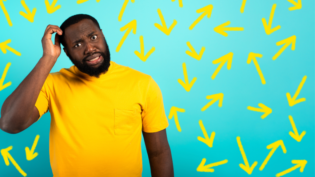 A man wearing a yellow shirt wonders what do with arrows pointing different directions all over.