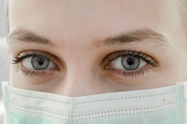 Woman with green eyes wearing a face mask.