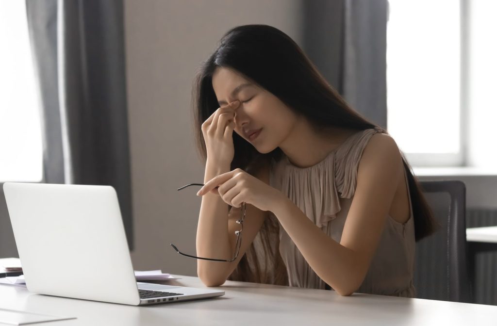 Young lady in front of her laptop frustrated due to dry eyes.