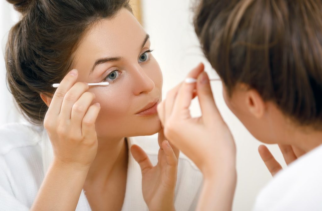 Young woman using cotton swaps to clean eyelids.