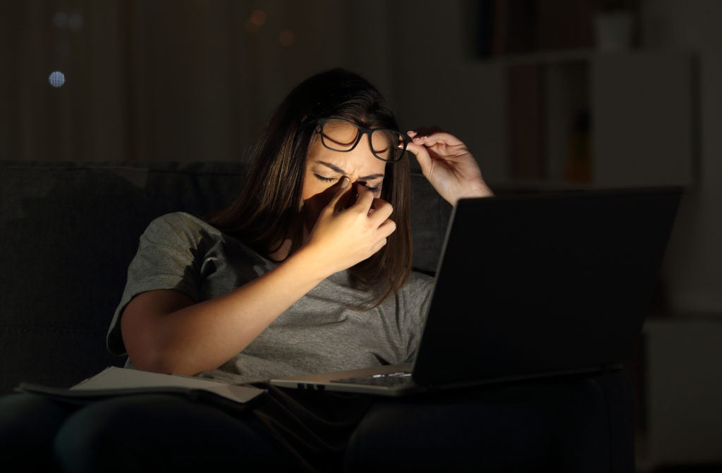 Tired woman suffering eyestrain studying in the night with a laptop at home