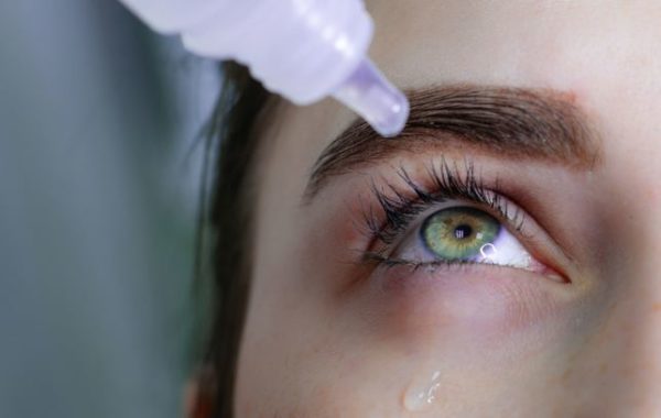 Close up of women with green eyes putting in eye drops for dry eye