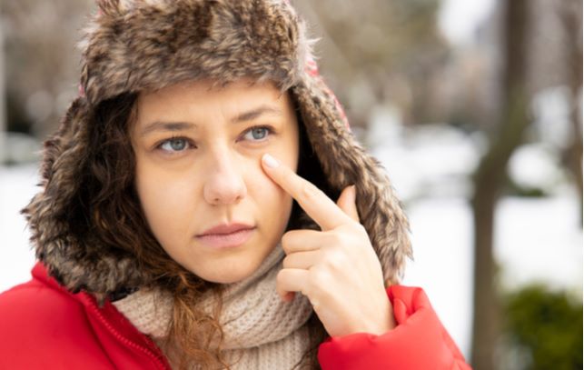 Women wearing hat and touching eye due to dry eyes during winter months