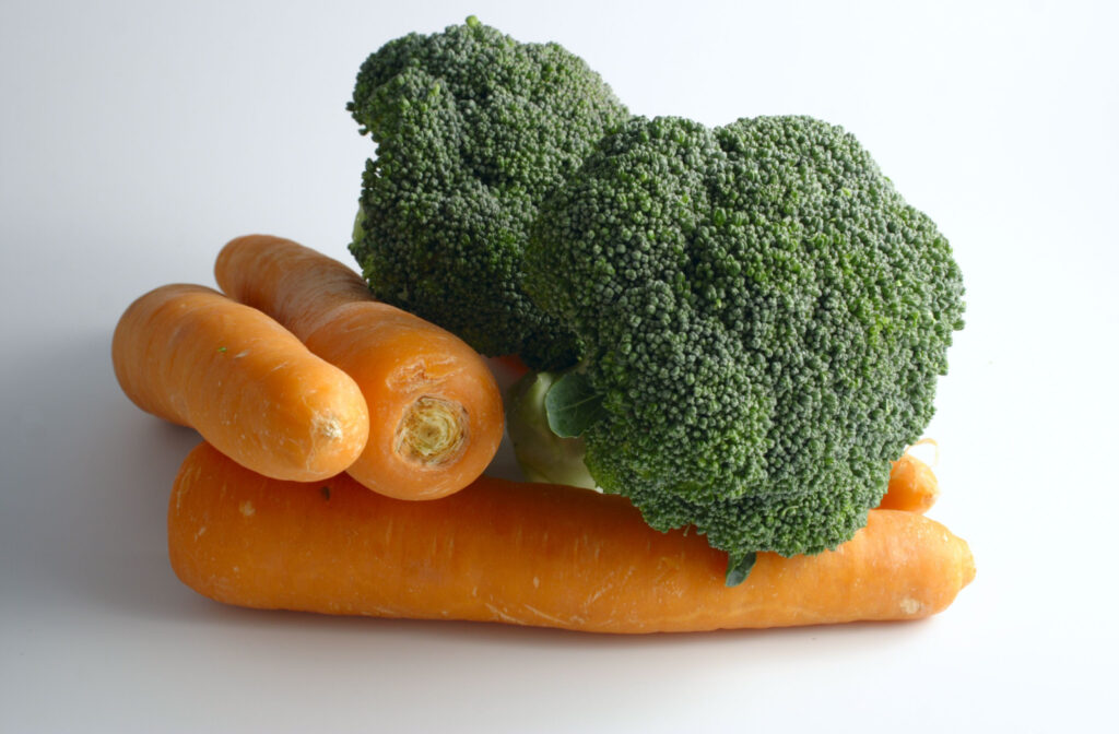 A bundle of carrots and broccoli against a white background.