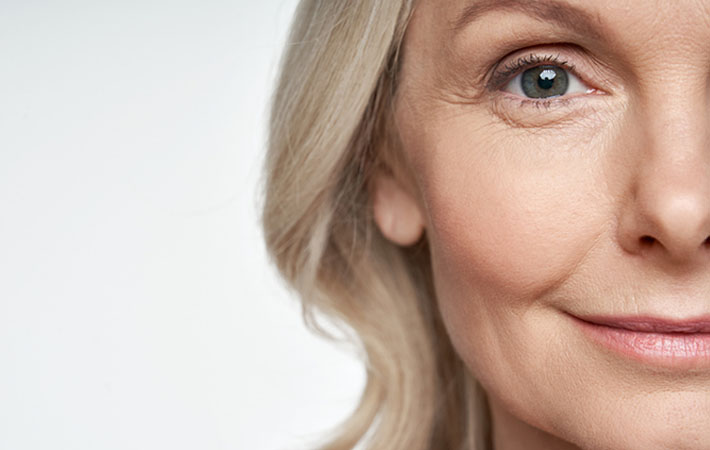 An older woman with fine lines and wrinkles and greying hair smiles at the camera thanks to her dry eye treatment with Jett Plasma Pen.
